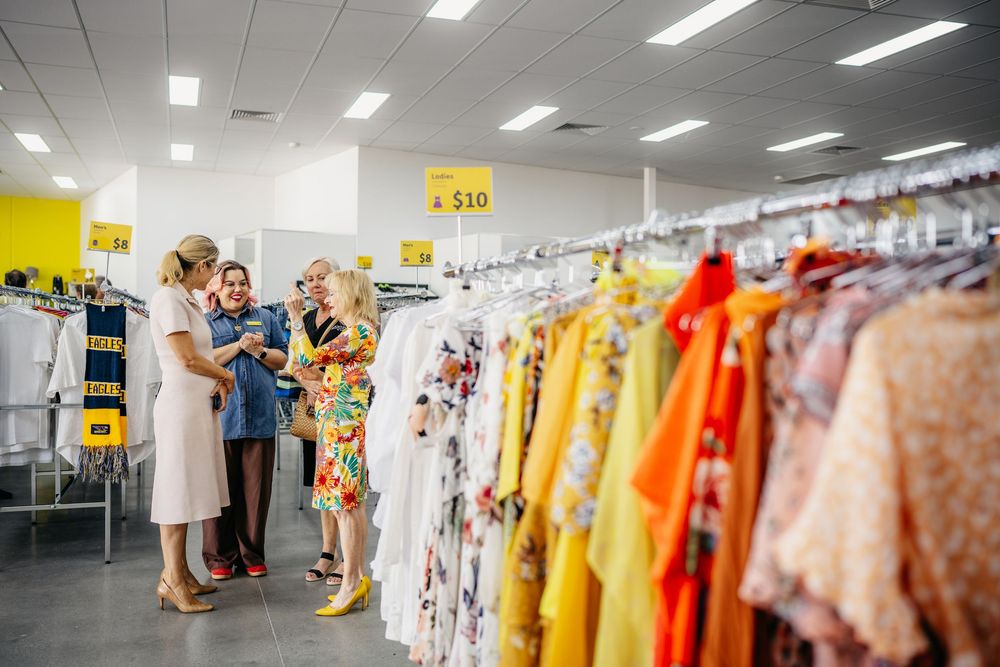 Shoppers browsing bright floral clothing racks inside a Good Sammy retail store.