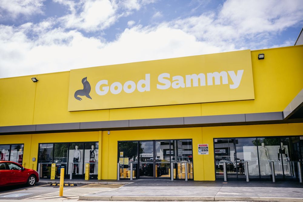Exterior of a bright yellow Good Sammy charity retail store on a cloudy day.