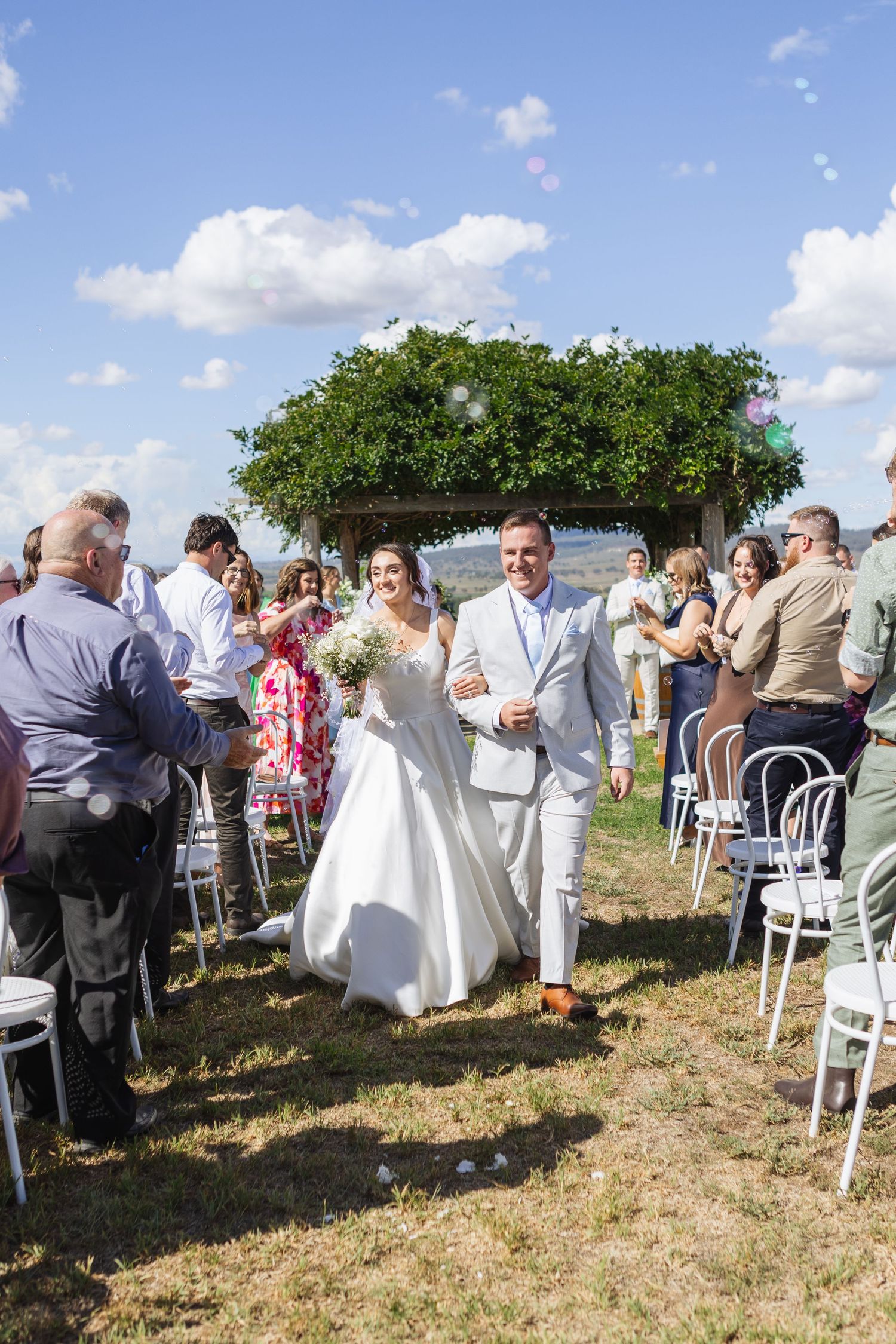 Bride and groom walking down aisle and smiling at Two Rivers Winery Wedding in Denman