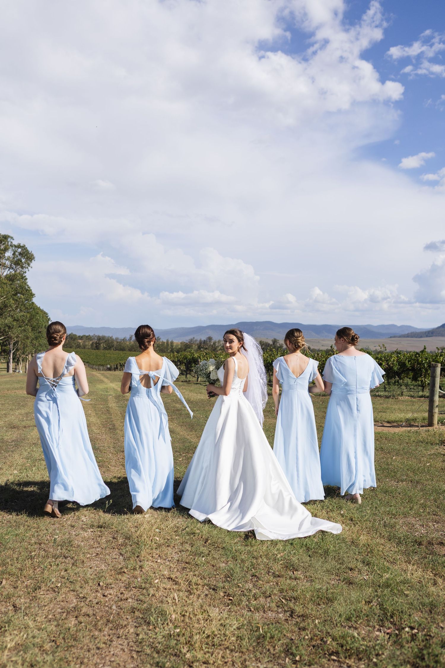 bridesmaids and bride walking in vineyard at Two Rivers Winery Wedding in Denman