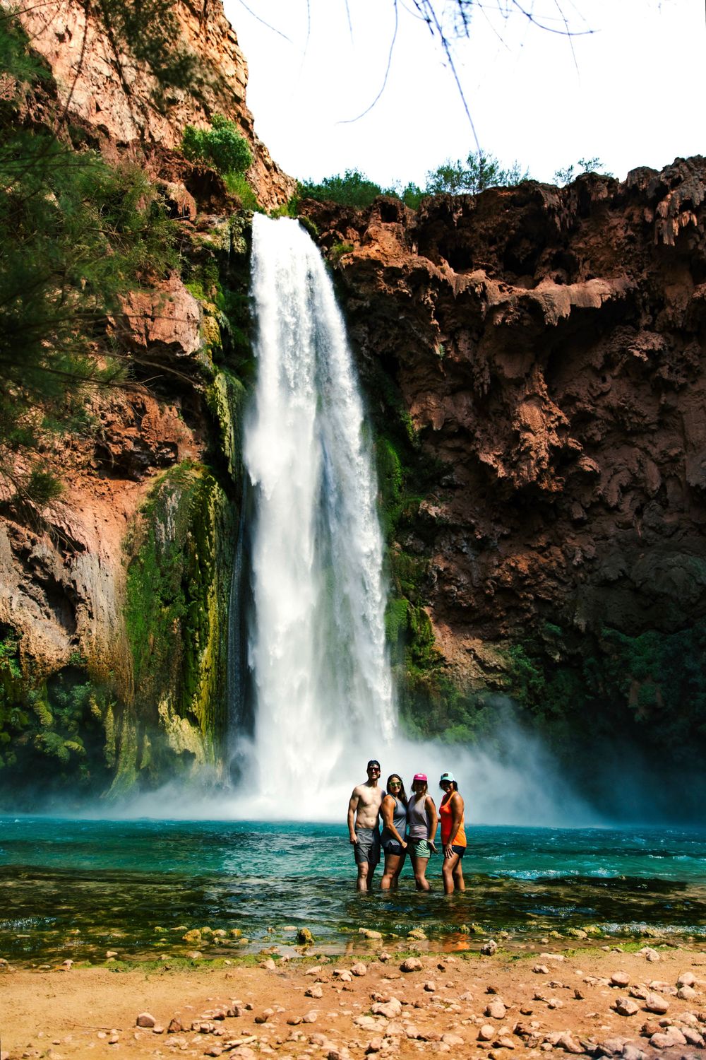 A group pose under the waterfall at Havasu Falls in the Grand Canyon.