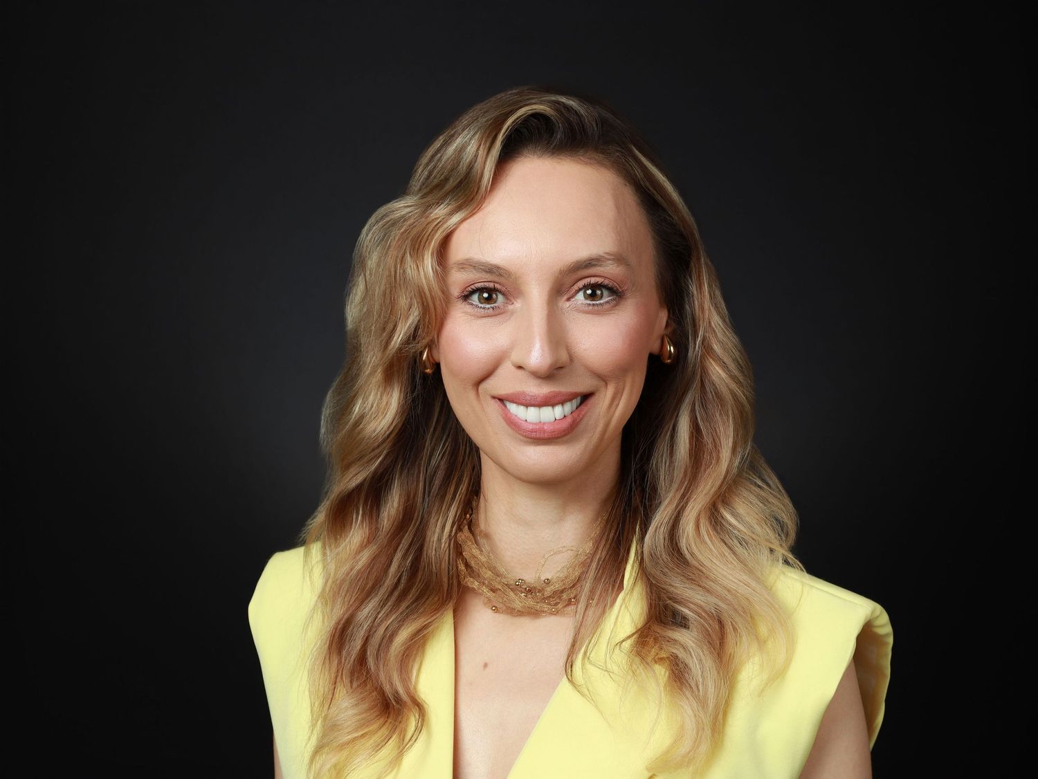 Усмихната жена с дълга руса коса в жълт топ — бизнес портрет от Headshot Studio София