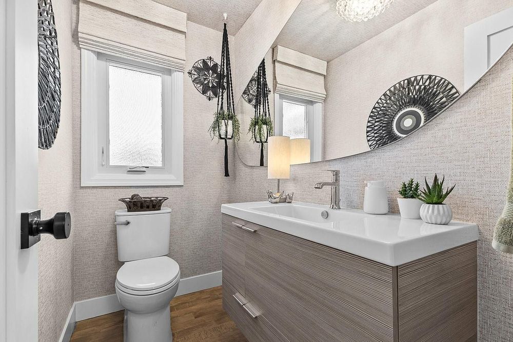 Contemporary bathroom with floating wood vanity, white countertop, decorative mirrors, and boho hanging plant accents.