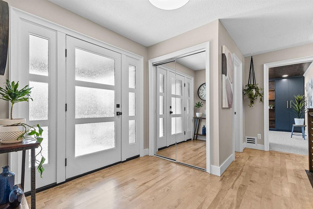 Bright entryway with white French doors, hardwood floors, and a hallway leading to a blue accent room.