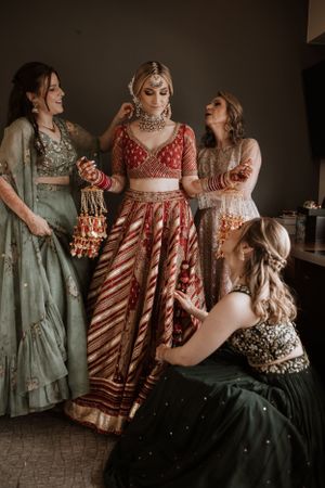 A group wearing traditional Indian attire in shades of red and mint green pose together during a celebration.
