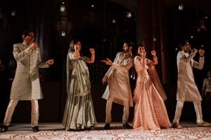 Dancers in elegant gowns perform choreographed moves on a dimly lit dance floor.
