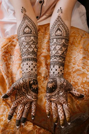 Intricate bridal mehndi henna designs covering both hands and forearms with traditional floral and geometric patterns.