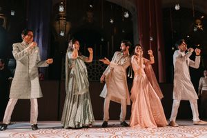 Group of five people in traditional Indian attire performing a coordinated dance at a wedding celebration.