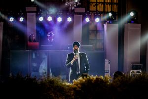Concert performance with dramatic purple stage lighting and spotlights.