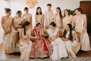 Wedding party in coordinated cream and red traditional Indian attire posed for a group photo.