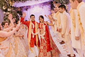 Wedding celebration with guests and couple performing traditional ceremonies under elegant decor.