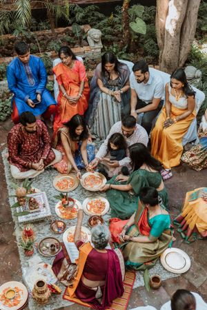 Group gathering for traditional Indian meal served on banana leaves outdoors.