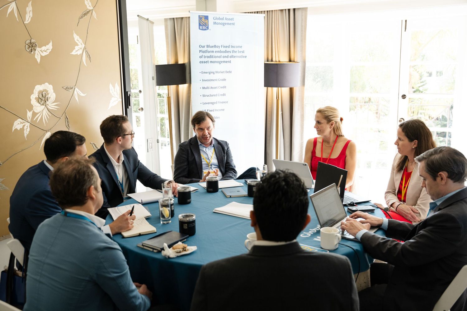 Business professionals engaged in a roundtable meeting discussion in a modern conference room setting.