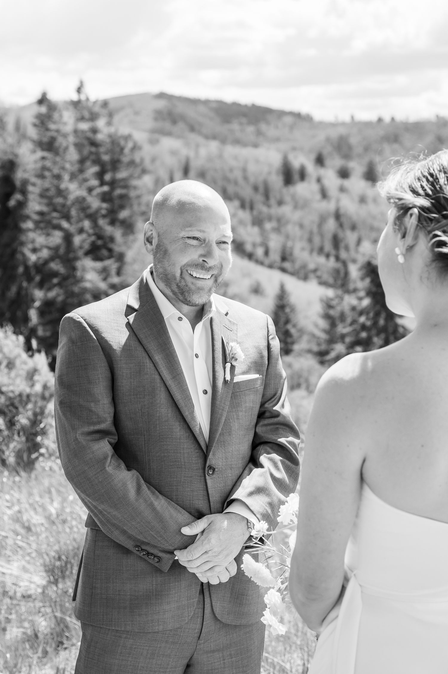 Groom smiling joyfully at bride during outdoor mountain wedding ceremony in black and white photo for Vail elopement