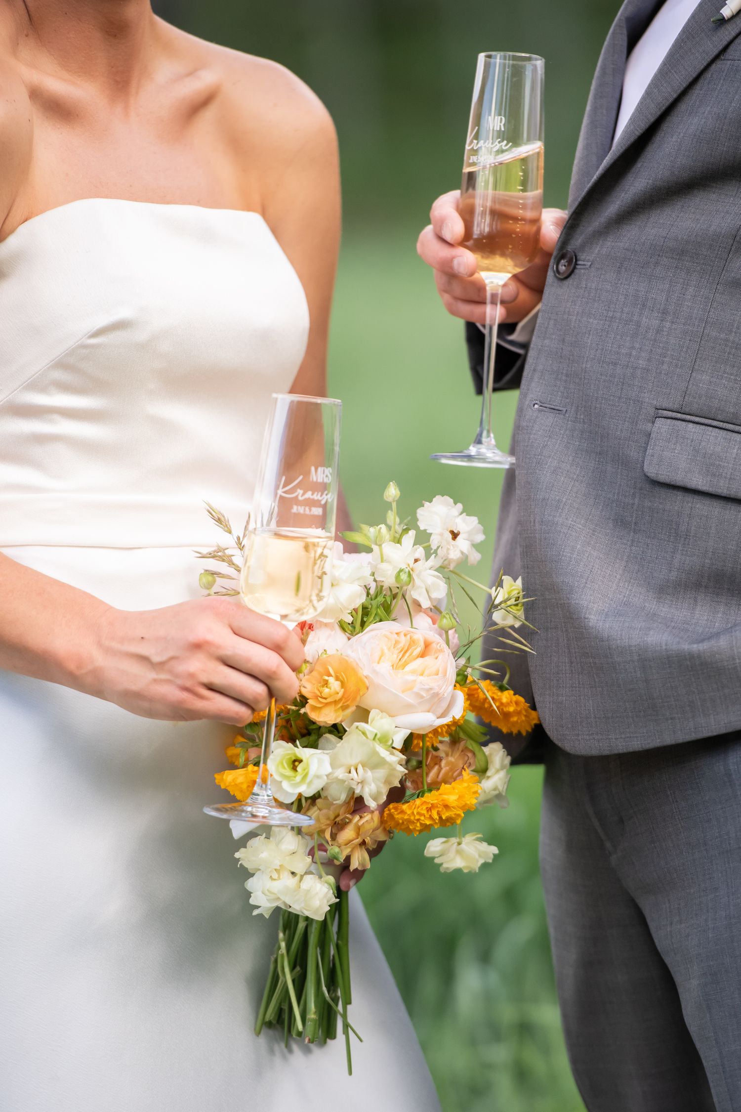 Bride holding a vibrant bouquet of peach roses, yellow marigolds, and white cosmos flowers in a white wedding dress for Vail elopement