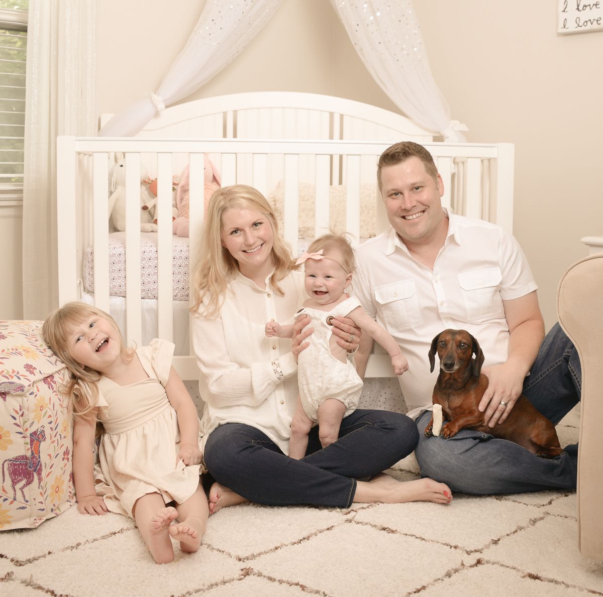 Family portrait in nursery room with dachshund puppy.