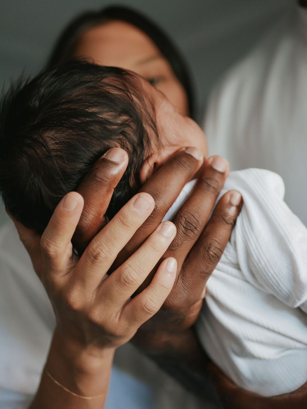 Mother tenderly cradling her newborn baby's head in her hands.