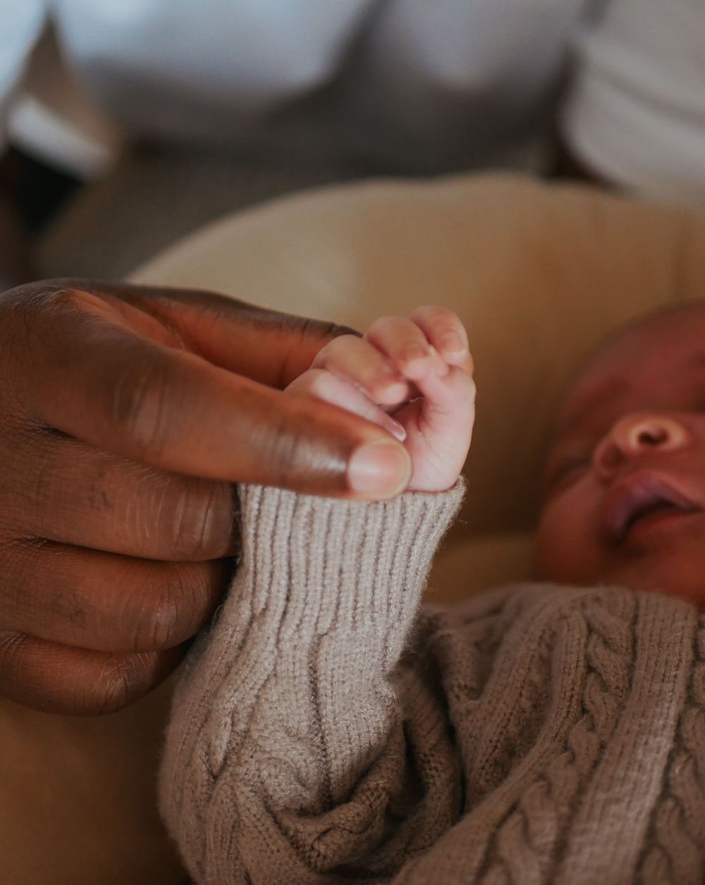 Parent's hand gently holding a newborn baby's tiny fingers in a tender moment.