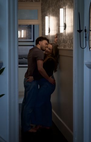 Couple sharing a tender moment kissing in a softly lit elegant hallway doorway.