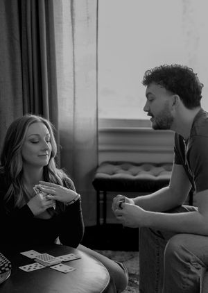 Black and white photo of a couple playing cards together at a small round table.