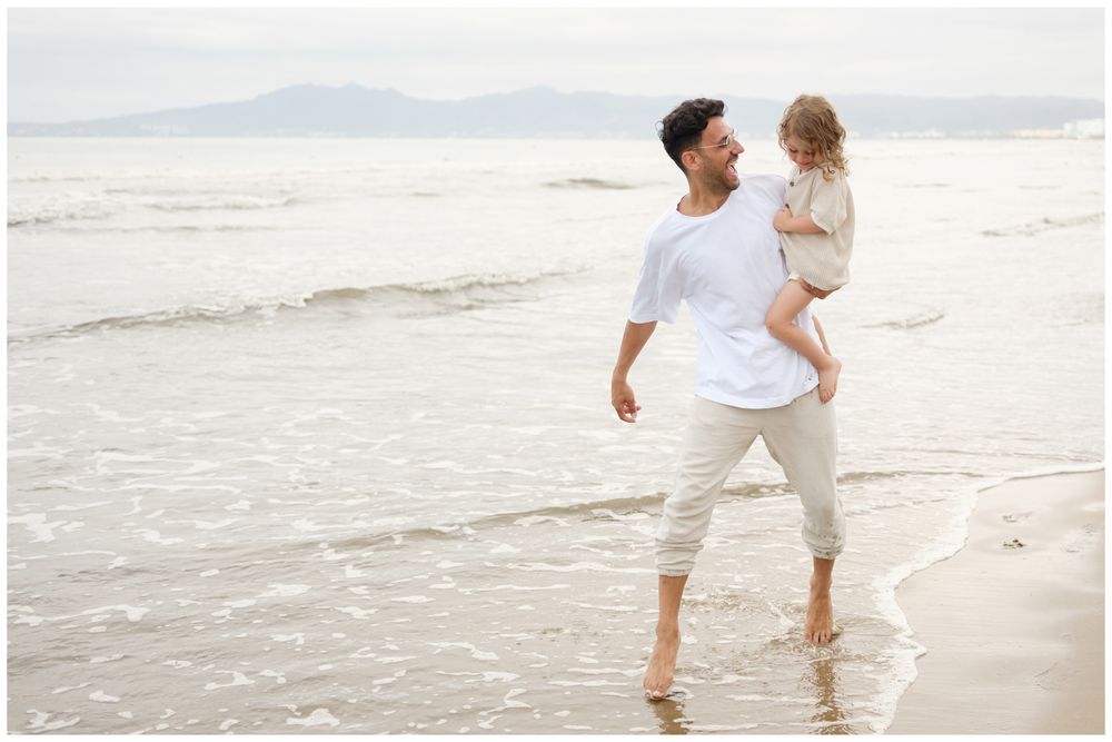 Father carrying his daughter while walking along the beach at Grand Velas Riviera Nayarit.