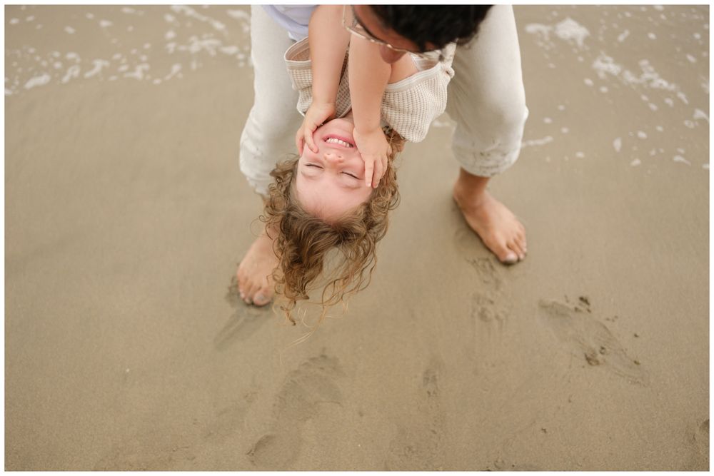 Father playing upside down with his daughter on the sand during a Punta Mita family photography session.