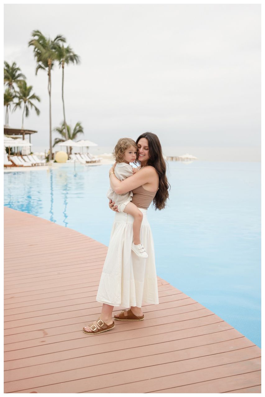 Mother holding her daughter beside the pool at Grand Velas Riviera Nayarit.
