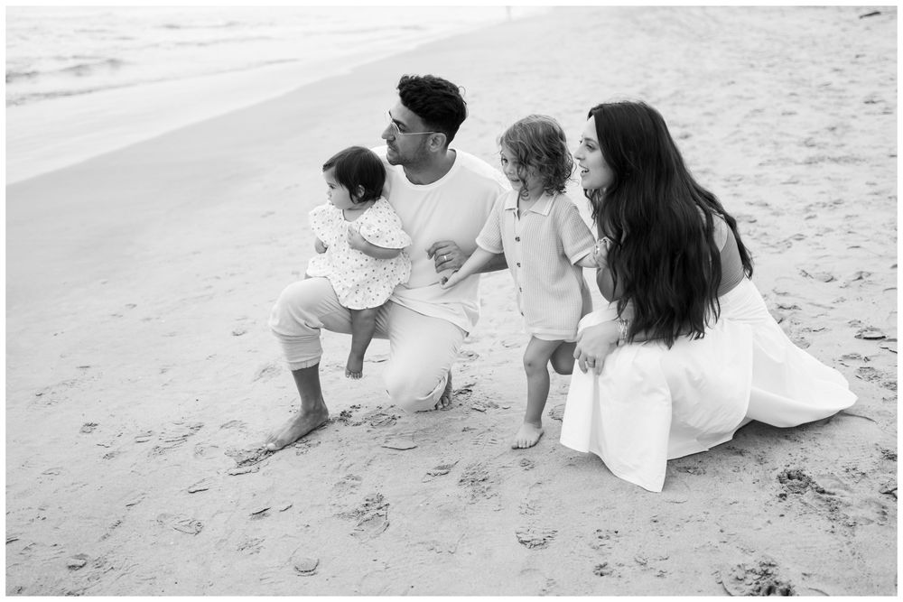Family sitting together on the beach during a black and white portrait session in Riviera Nayarit.