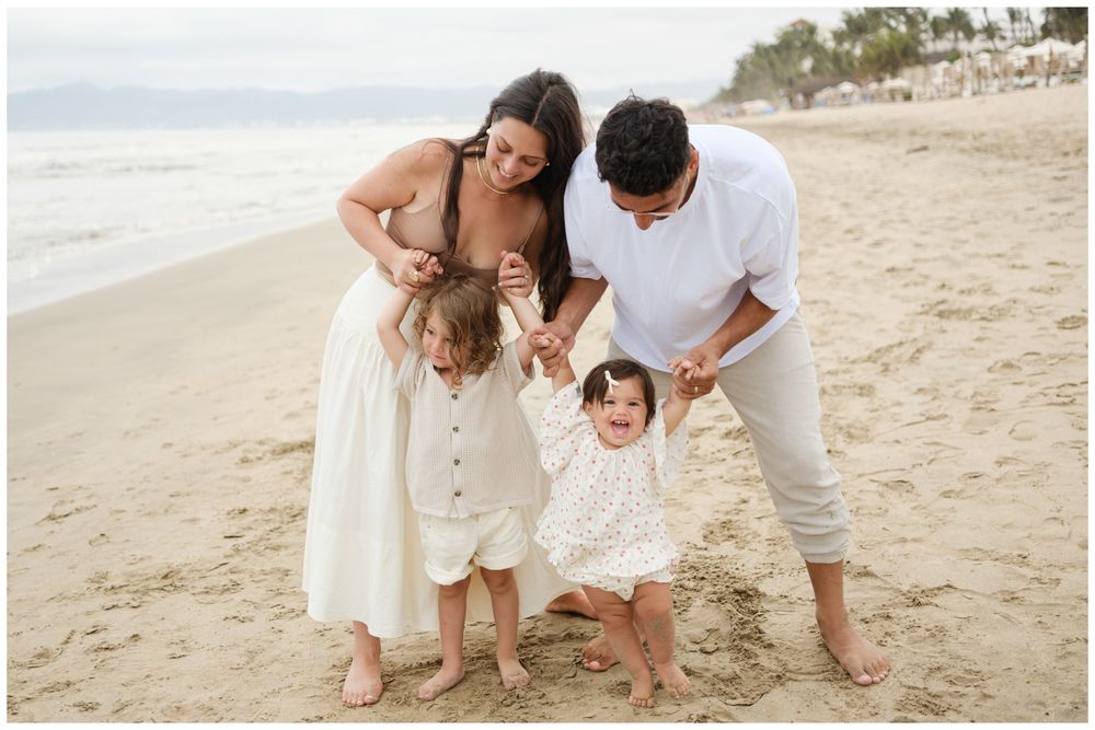 Parents playing with their children by the ocean during a family photo session in Punta Mita.