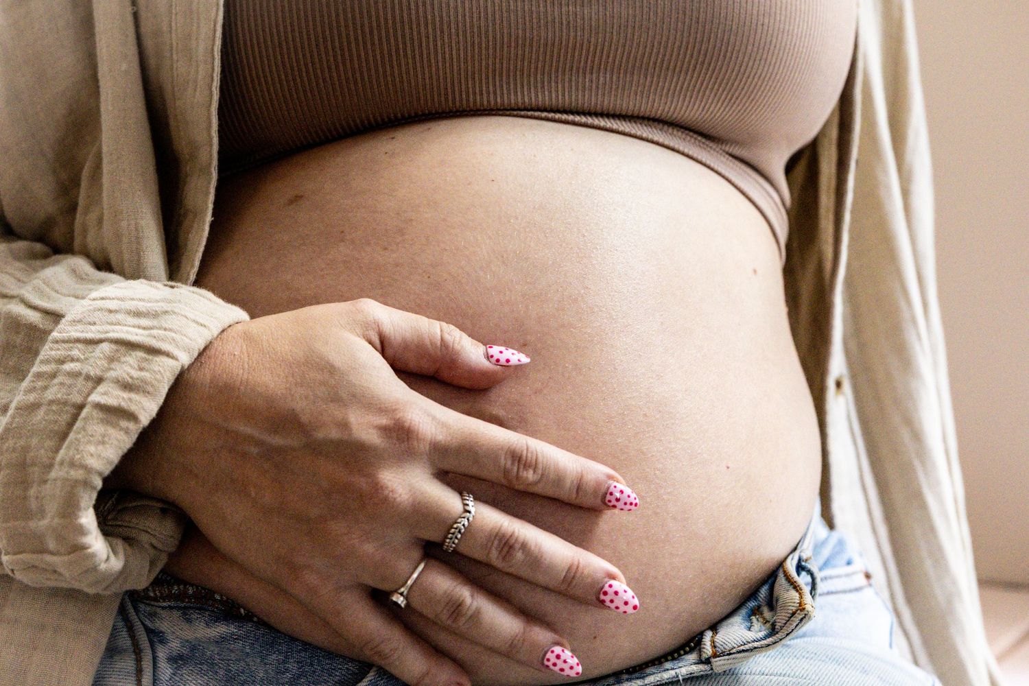 Couple lying on bed with small dog wearing orange bandana, ultrasound photos displayed in front, announcing pregnancy.