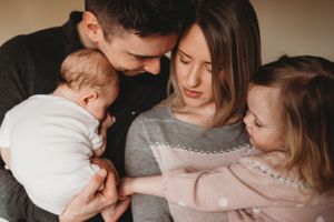 An intimate family moment captured as they gather close together with their young children.
