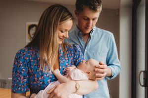 Parents sharing tender moment with newborn baby in home setting.