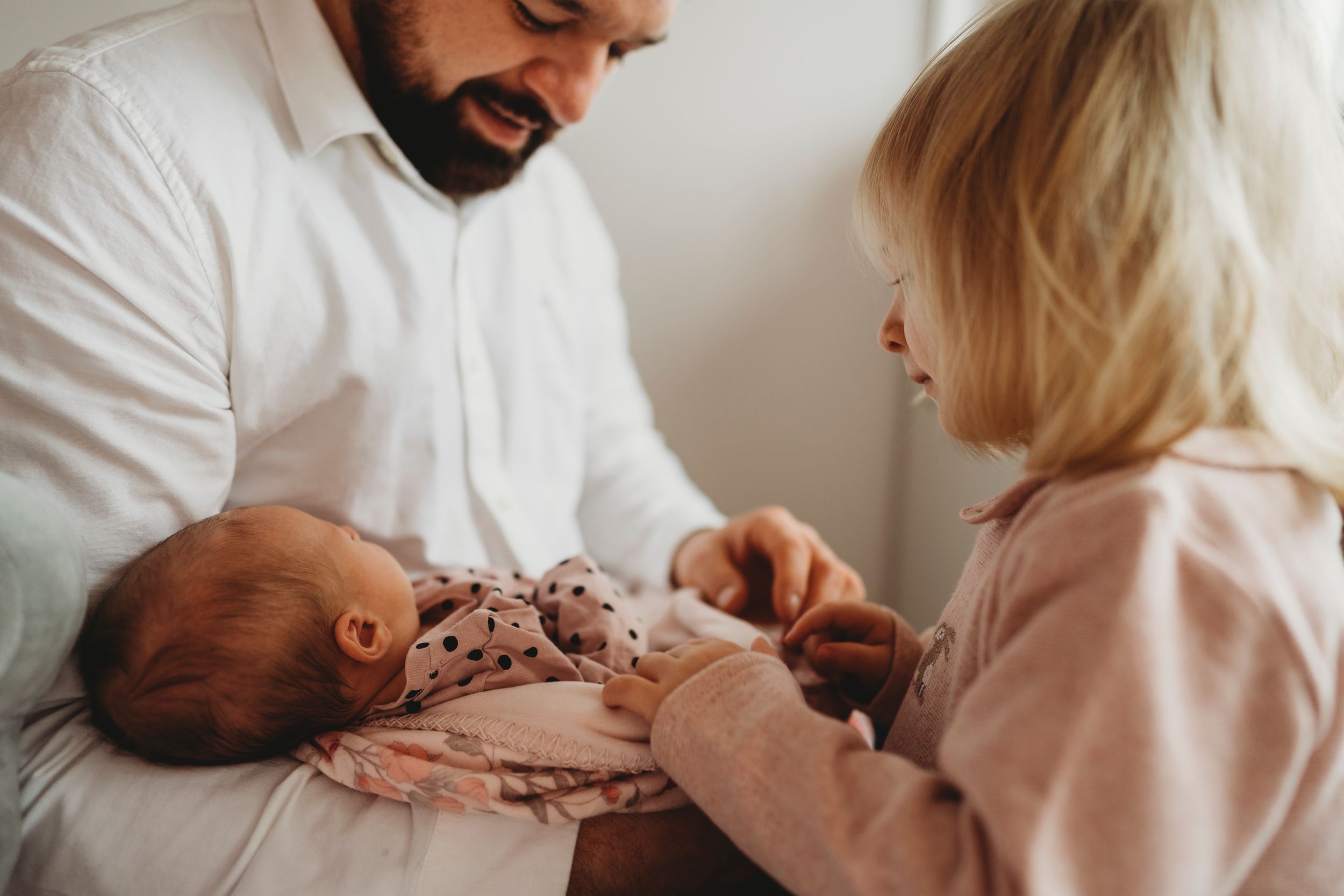 An intimate family moment welcoming a newborn baby in soft, warm tones.