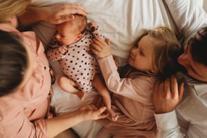 A loving family moment captured on white bedding in soft natural light.