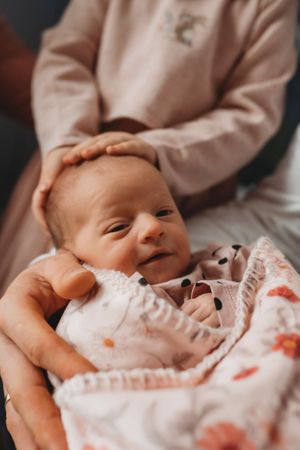 A smiling newborn baby lying contentedly in soft pink clothing.