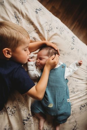 Young siblings sharing tender moment on floral bedding.