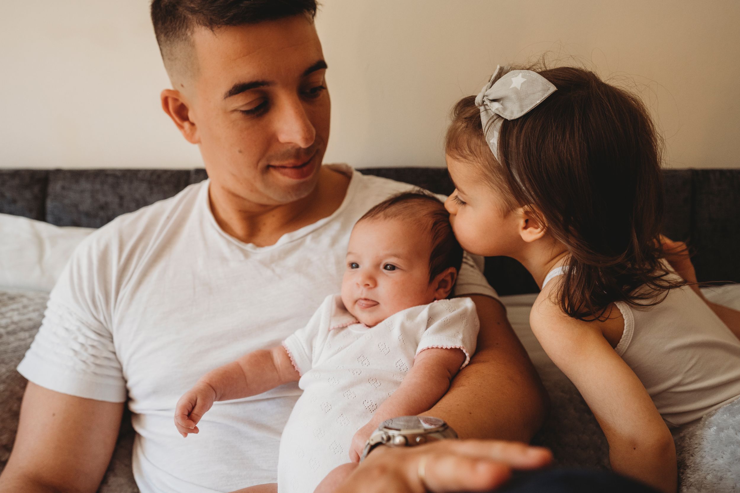 Family shares intimate moment with newborn baby on couch.