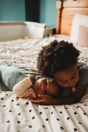 Two children sharing a tender moment while resting on a polka dot bedspread.