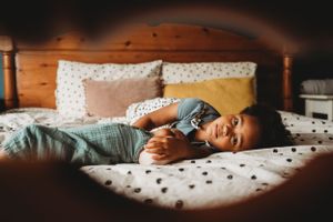 A child relaxing peacefully on a polka dot bedspread in warm lighting.