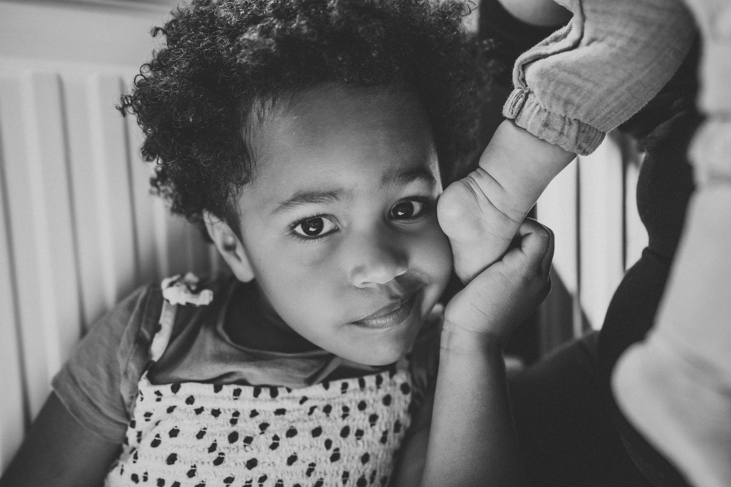 A charming portrait of a child in a polka dot top against a light background.