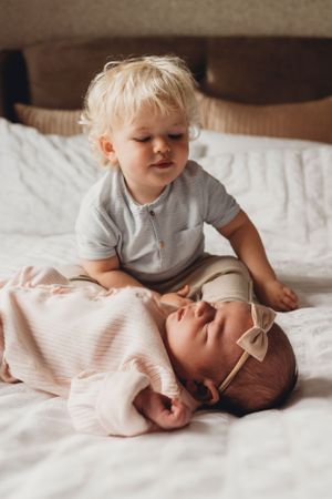 Two young children sharing a sweet moment together on white bedding.