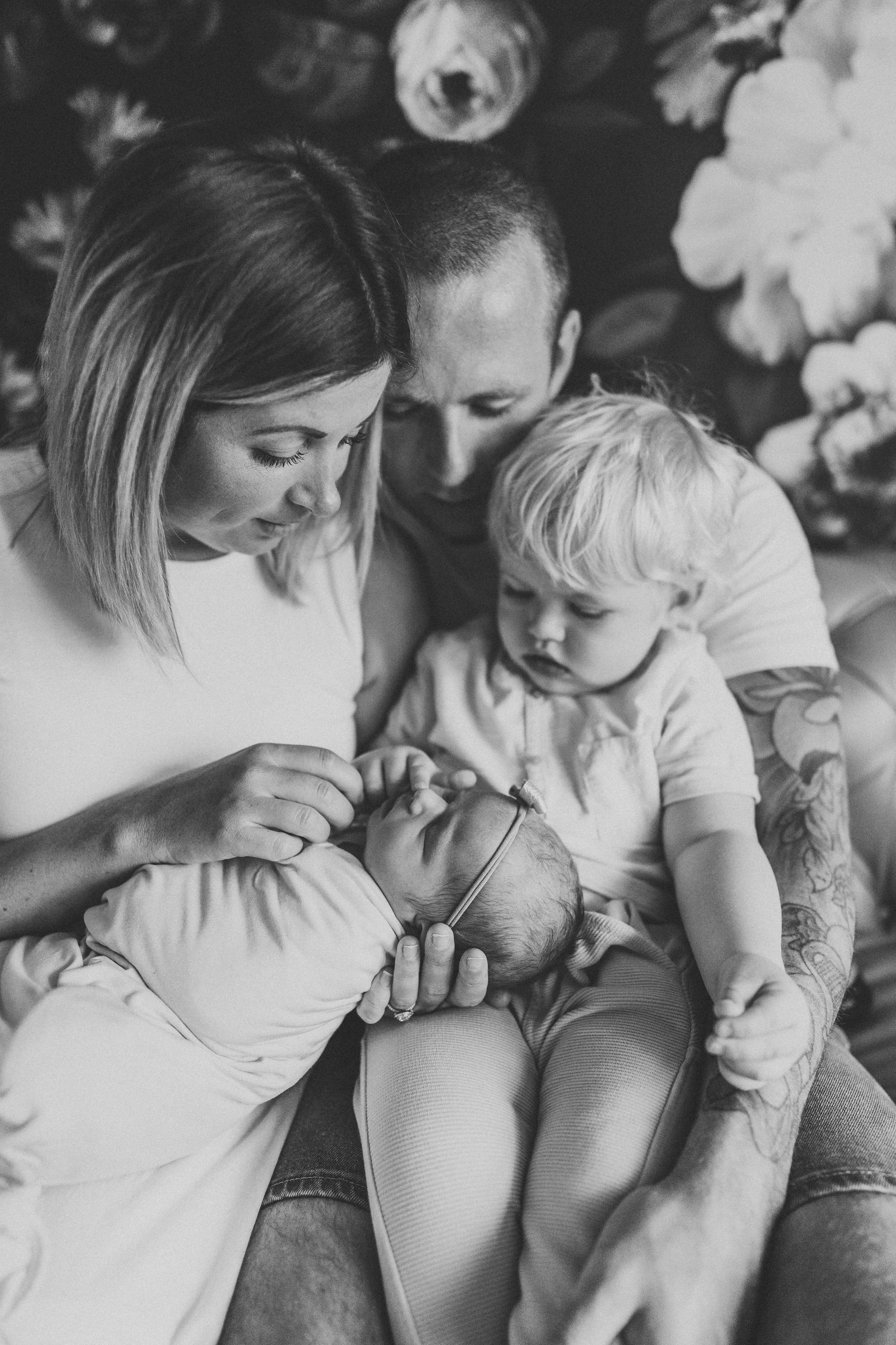 A black and white family portrait showing tender moments between loved ones on a couch.