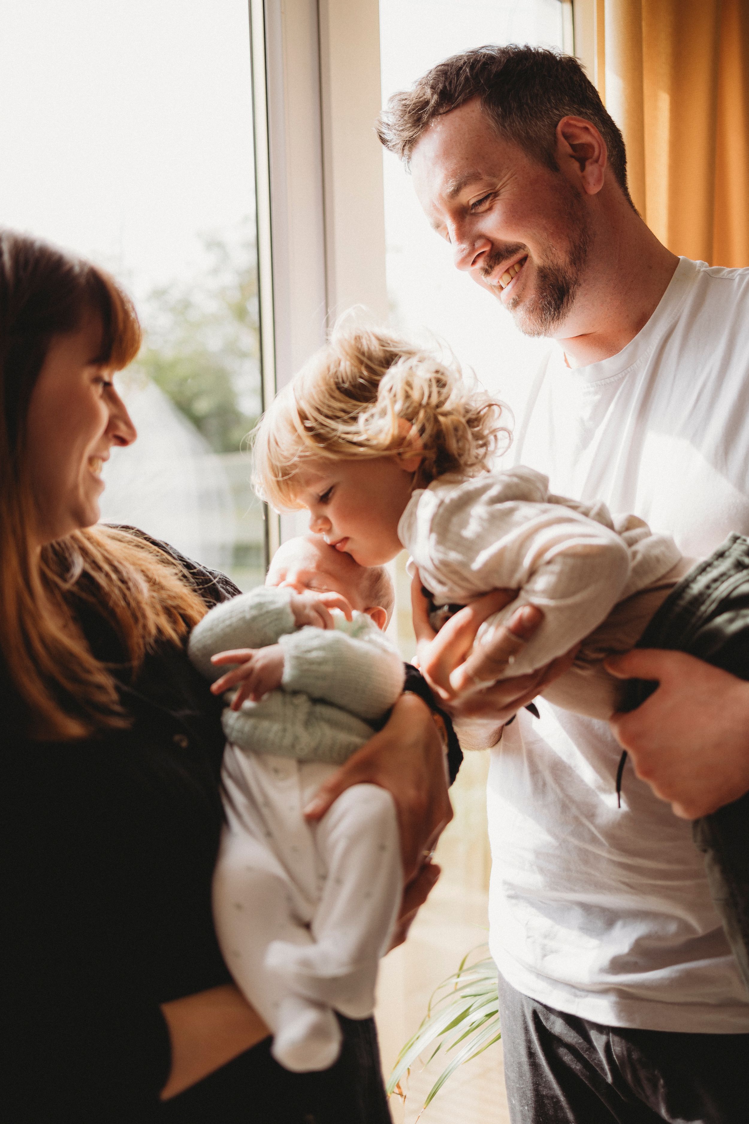 Tender family moment by window as parents share time with young child.