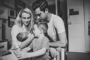 A black and white family portrait showing parents and children gathered intimately together indoors.