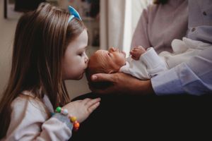 A tender moment of bonding with a newborn baby in white clothing.