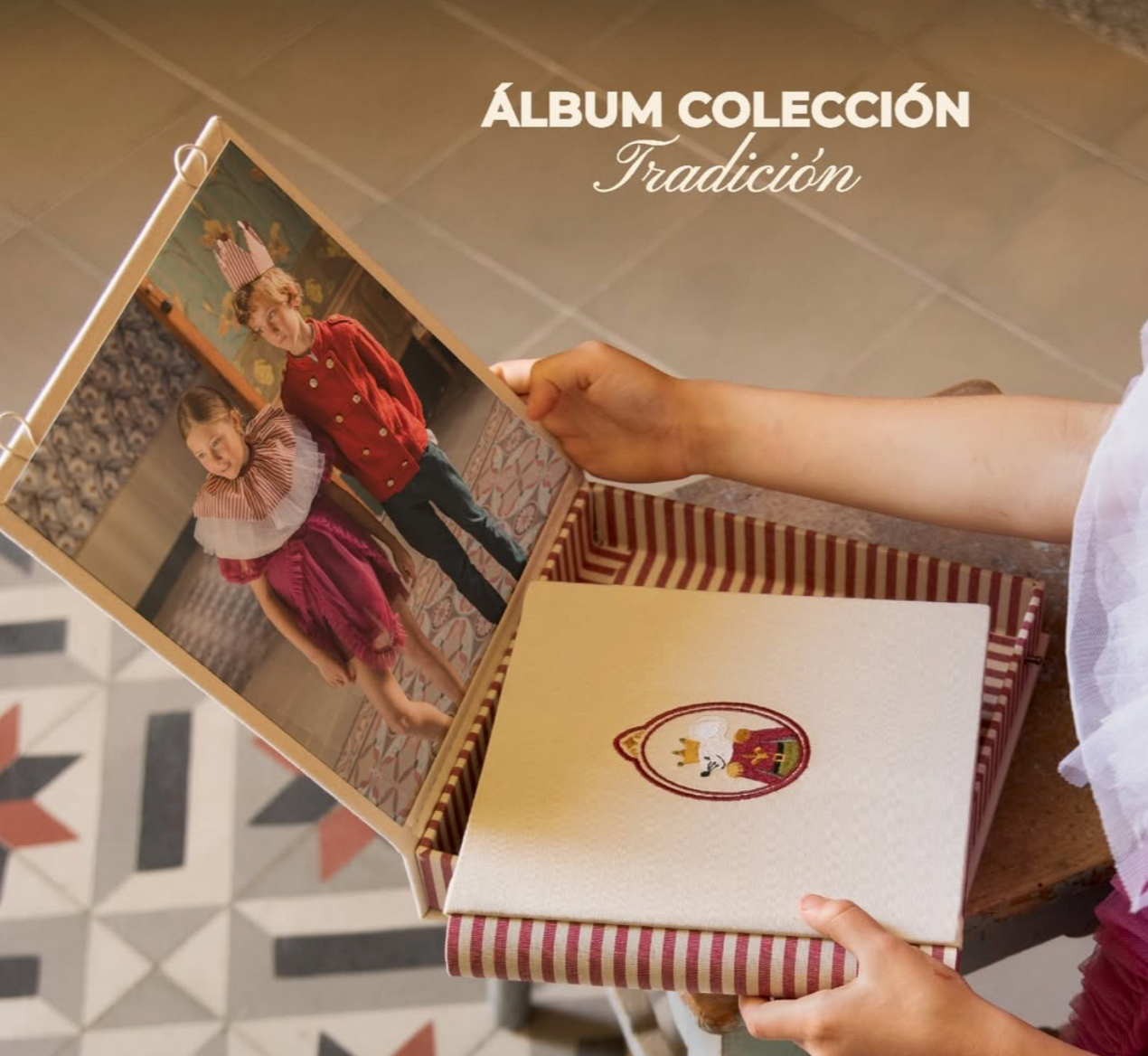 Hands holding an open photo album from the Tradicion collection, displaying family photos with a decorative striped box below.