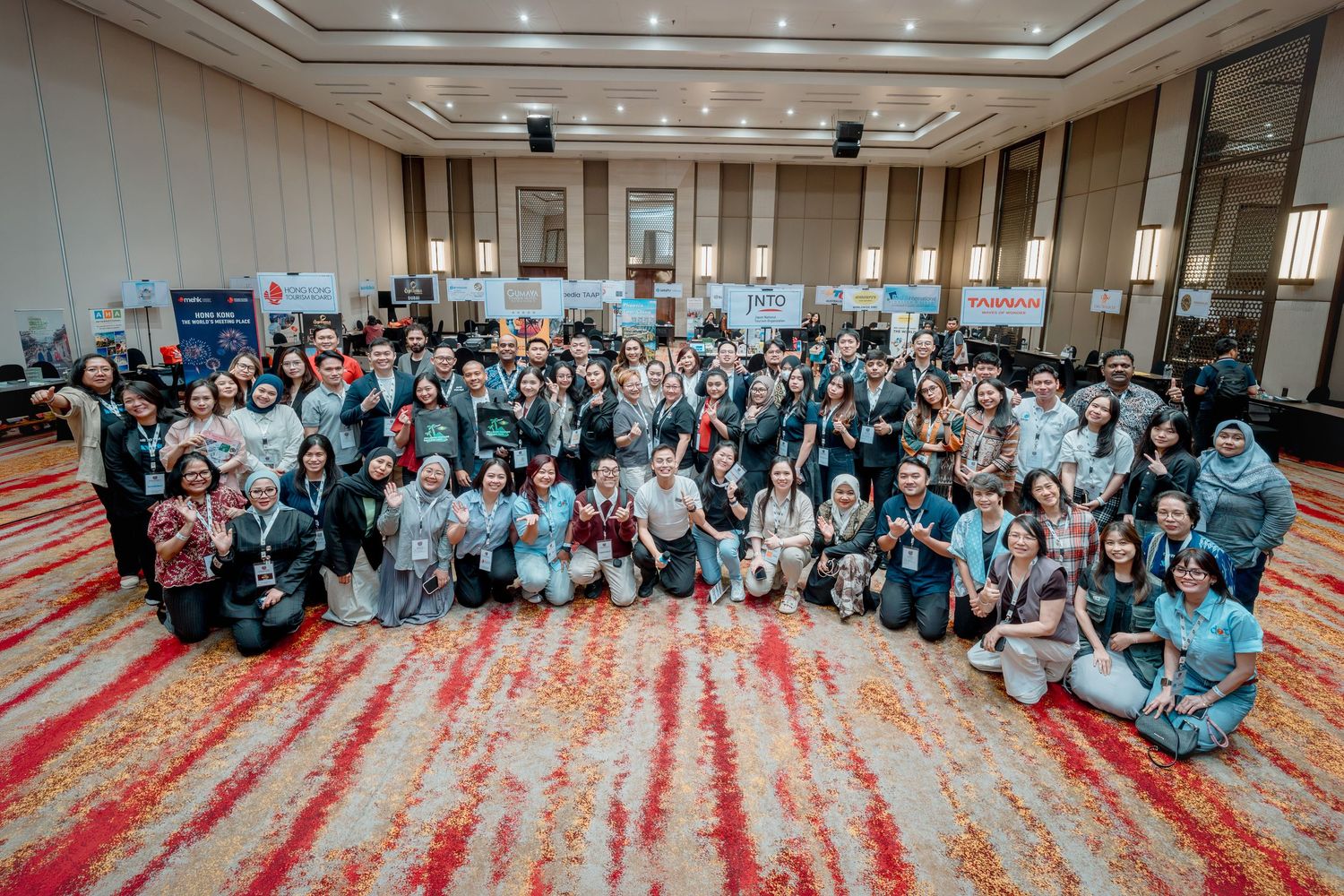 Large group of diverse professionals posing together in a decorated conference hall for a corporate event photo.