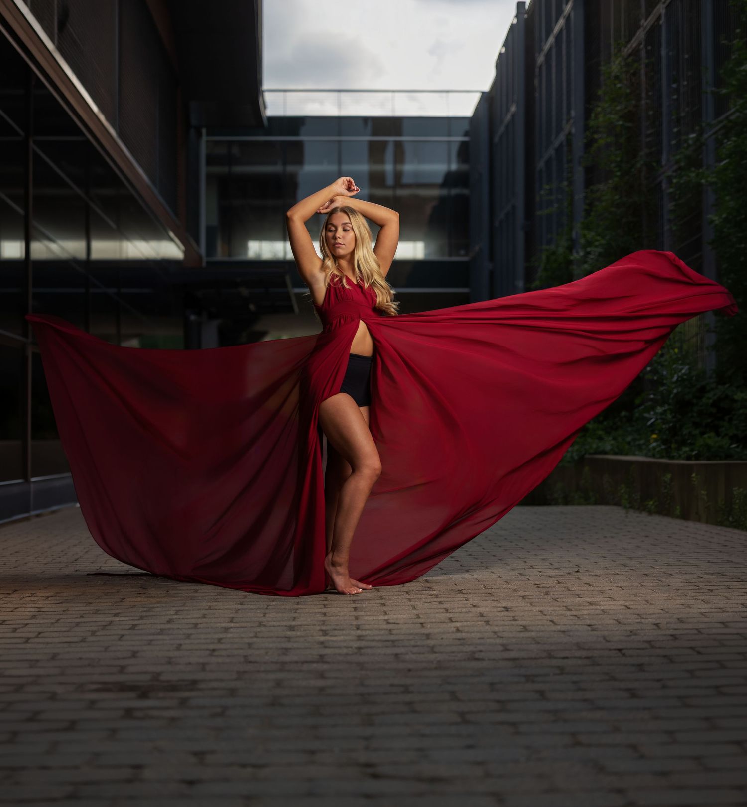 Dramatic senior portrait of a girl posing with a flowing red dress