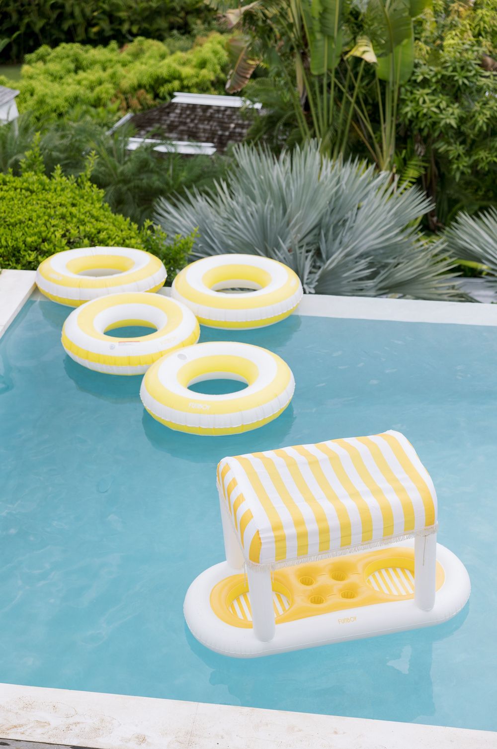 Yellow and white inflatable pool rings and striped float bar in a luxury outdoor swimming pool.