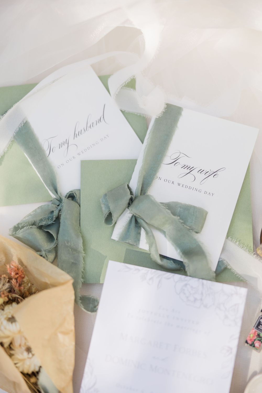 Sage green wedding gift bags with white cards reading to my husband and to my wife tied with dusty blue silk ribbons.